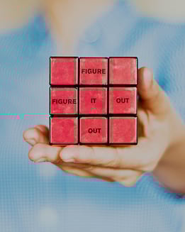 A hand holding a Rubik's cube facing the red side