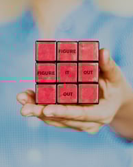 A hand holding a Rubik's cube facing the red side