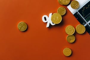 Gold coins and a percentage symbol on a dark red table